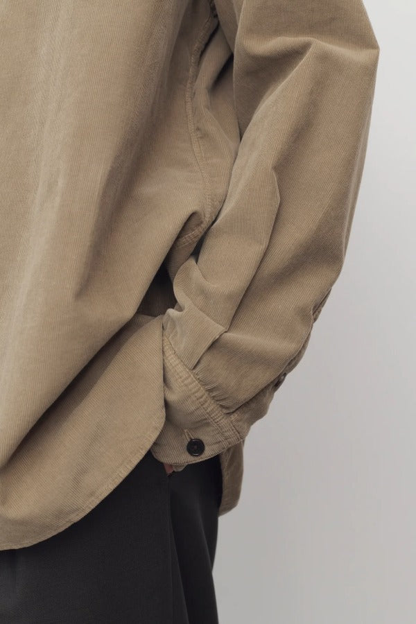 Side closeup view of beige corduroy sislia shirt on model wearing grey pants, against a white background.