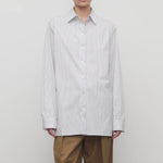 Front view of blue/white cotton sisilia shirt on model wearing camel trousers, against a white background.