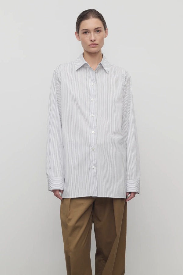 Front view of blue/white cotton sisilia shirt on model wearing camel trousers, against a white background.