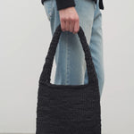 Front view of black Didion Shoulder bag on model wearing light-colored jeans and a black sweater, on a white background.