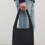 Front view of black Didion Shoulder bag on model wearing light-colored jeans and a black sweater, on a white background.