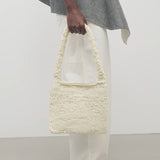 Front view of ivory didion shoulder bag on model wearing white pants with grey sweater, against a white background.