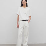 Front view of white eglitta jean on model wearing white t-shirt and sneakers, against a white background.