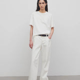 Front view of white eglitta jean on model wearing white t-shirt and sneakers, against a white background.