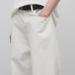 Front closeup view of white eglitta jean on model wearing white t-shirt, against a white background.