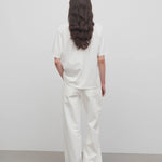 Back view of white eglitta jean on model wearing white t-shirt, against a white background.