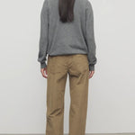 Back view of beige eglitta pant on model wearing grey sweater and boots, against a white background.