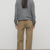 Back view of beige eglitta pant on model wearing grey sweater and boots, against a white background.