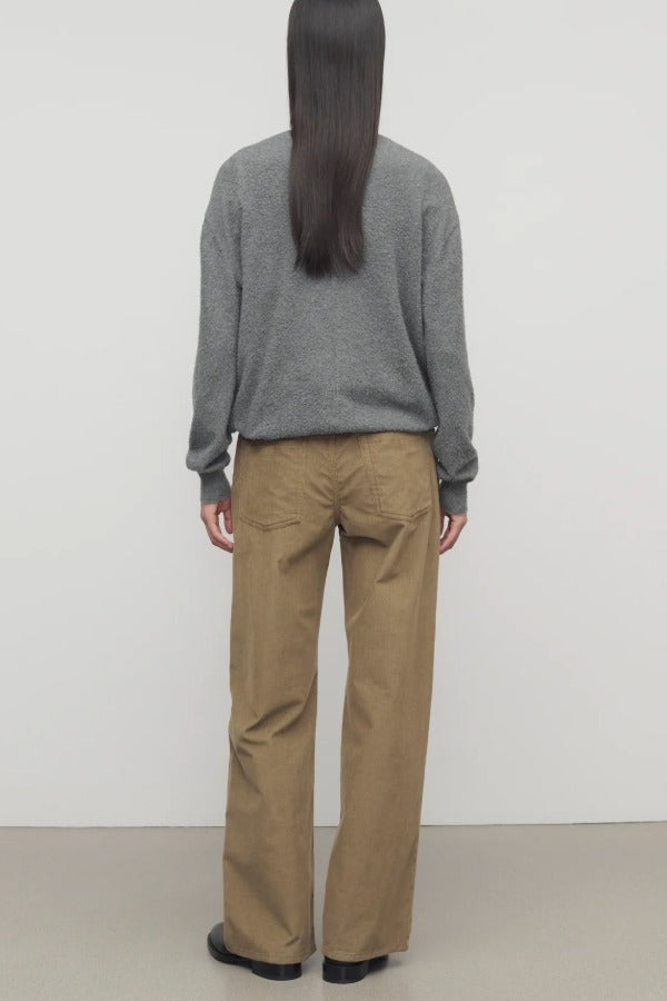 Back view of beige eglitta pant on model wearing grey sweater and boots, against a white background.