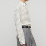 Side view of grey stripe shirt on model wearing grey trousers, against a white background.
