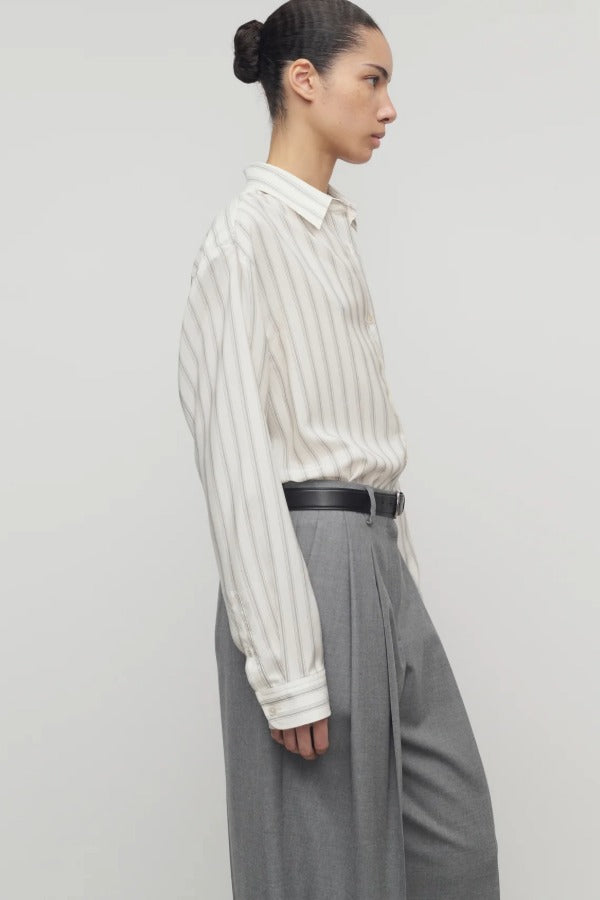 Side view of grey stripe shirt on model wearing grey trousers, against a white background.