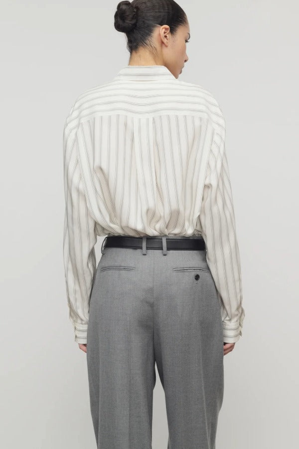 Back view of grey stripe shirt on model wearing grey trousers, against a white background.