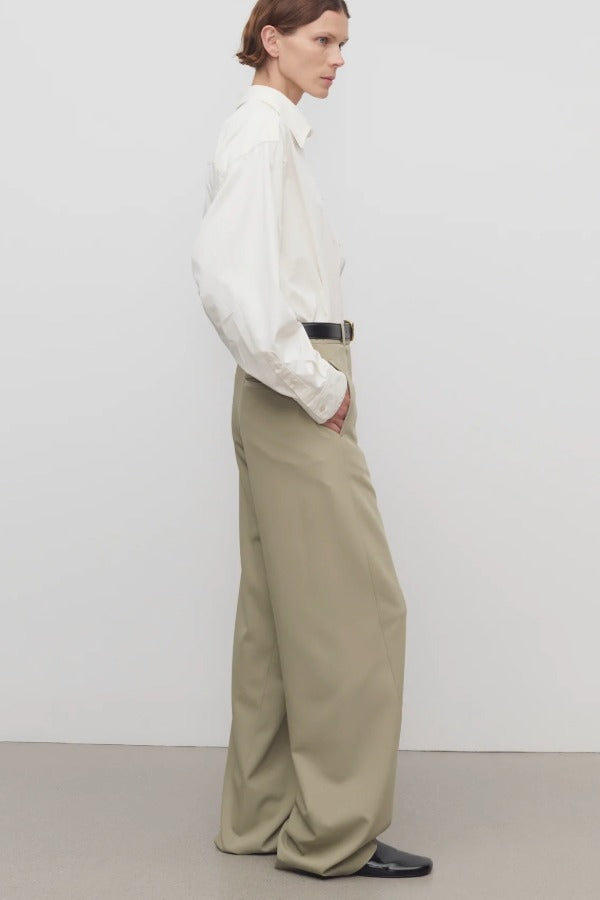 Side view of fossil elowyn pant on model wearing white shirt and heels, against a white background