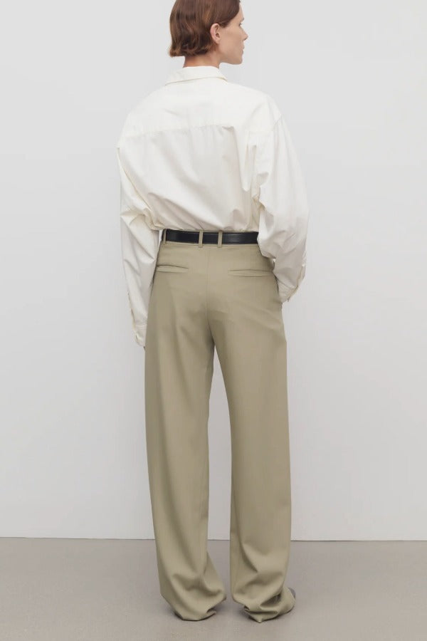 Back view of fossil pant on model wearing white shirt and black heels, against a white background.