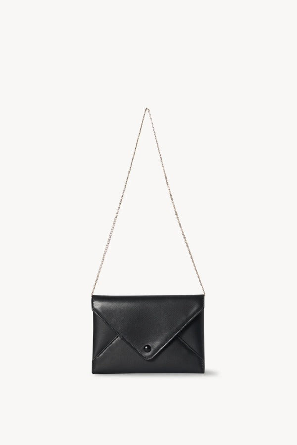 Strap view of black envelope clutch on white background, with no model shown.