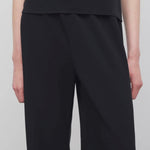 Front closeup view of black gala pant on model wearing black top, against a white background.