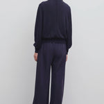 Back view of navy gala pant on model wearing black top, against a white background.