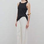 Front slanted view of off white gala pant on model wearing black tank top, against a white background.
