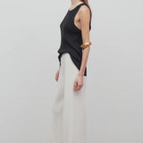 Side view of off white gala pant on model wearing black tank top, against a white background.