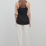 Back view of off white gala pant on model wearing black tank top, against a white background.
