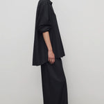 Side view of black gala pant on model wearing black shirt and heels, against a white background.