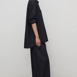 Side view of black gala pant on model wearing black shirt and heels, against a white background.