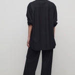 Back view of black gala pant on model wearing black shirt and heels, against a white background.