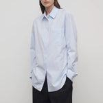 Front slanted view of sky blue gavina shirt on model wearing black pants, against a white background.