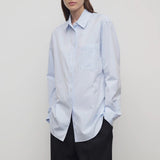 Front slanted view of sky blue gavina shirt on model wearing black pants, against a white background.