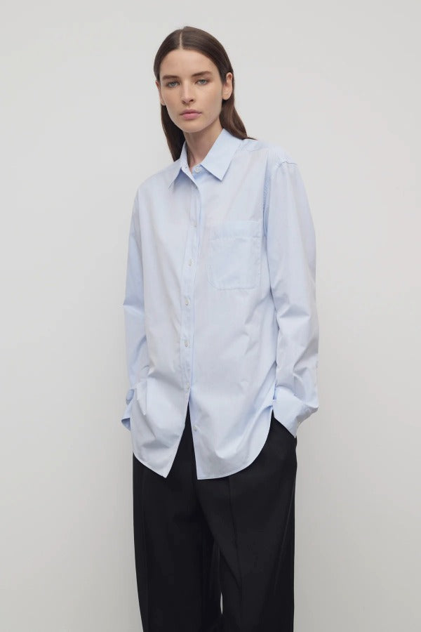 Front slanted view of sky blue gavina shirt on model wearing black pants, against a white background.