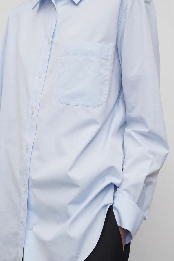 Front closeup view of sky blue gavina shirt on model wearing black pants, against a white background.