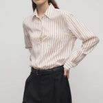 Front slanted view of ivory/cinnamon gavina shirt on model wearing black pants, against a white background.