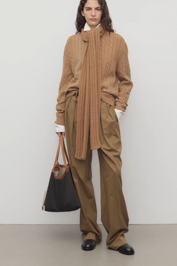 Front view of dark sand igor pant on model wearing camel sweater and boots, against a white background.