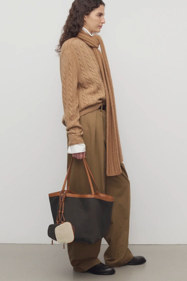 Side view of dark sand igor pant on model wearing camel sweater and boots, against a white background.