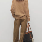 Back view of dsark sand igor pant on model wearing camel sweater and boots, against a white background.