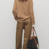 Back view of dsark sand igor pant on model wearing camel sweater and boots, against a white background.