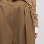 Front closeup view of dark sand igor pant on model wearing camel sweater, against a white background.