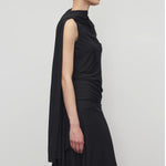 Side view of black isadra top on model wearing black skirt, against a white background.