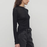 Side view of black iverness top on model wearing black jeans and belt, against a white background.