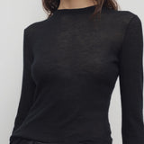 Front closeup view of black iverness top on model wearing black jeans and belt, against a white background.