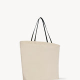 Side slanted view of the ivory mesh and leather bag is pictured on a white background, with no model shown.