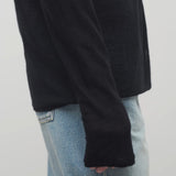 A model wears the long sleeve black knit cardigan with baggy jeans and is shown   at a sideview glance on a white backdrop