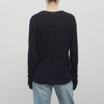 A model with light brown hair wears the long sleeve black knit cardigan with baggy jeans shown backside with a white backdrop.