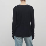 A model with light brown hair wears the long sleeve black knit cardigan with baggy jeans shown backside with a white backdrop.