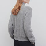 Back view of medium heather grey top on model wearing black trousers, against a white background.