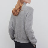 Back view of medium heather grey top on model wearing black trousers, against a white background.