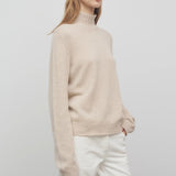 Front slanted view of oatmeal kensington top on model wearing white trousers, against a white background.