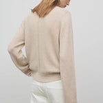 Back view of oatmeal kensington top on model wearing white trousers, against a white background.