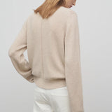 Back view of oatmeal kensington top on model wearing white trousers, against a white background.