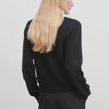 Back view of black kensington top on model wearing black trousers, against a white background.